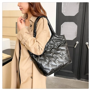 Dettaglio di una grande borsa tote trapuntata nera indossata da una modella elegante