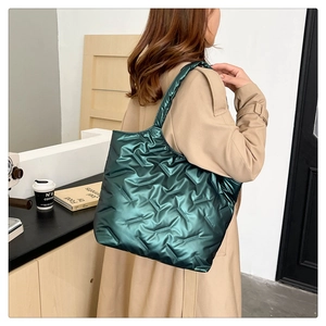 Detail of quilted puffy tote bag in metallic green fabric with elegant shoulder strap