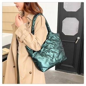Detailed view of dark green quilted tote bag with metallic finish and thick shoulder strap