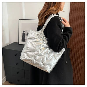 Quilted silver tote bag with wide shoulder strap shown in a minimalist urban setting