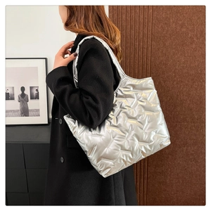 Dettaglio della borsa tote trapuntata argento metallizzato indossata su un cappotto
