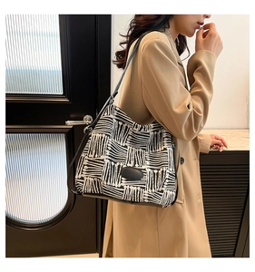 Detail of checkered shoulder tote bag with black leather straps on camel blazer model