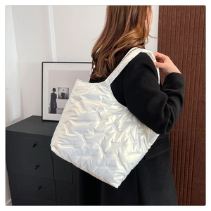 Fashionable white glossy quilted tote bag shown in a stylish shoulder carrying style
