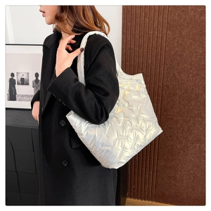 Vista laterale di una borsa tote trapuntata argento con finitura metallizzata e tracolla