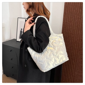 Detail of a large silver quilted tote bag with padded handles on a model shoulder