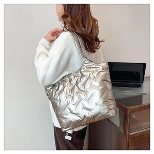 Silver metallic quilted puffer tote bag shown on model in a professional office setting