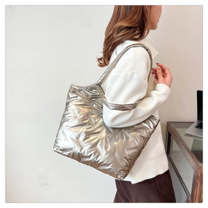 Vista laterale di una grande borsa tote trapuntata argento metallizzato sul modello