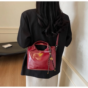 Détail du sac cabas bordeaux avec logo triangle, breloque en corde et fini brillant