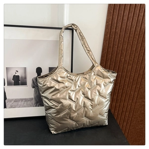 Detailed view of quilted puffer tote bag with metallic champagne gold finish and wide strap