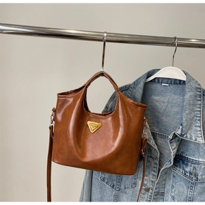 Détail d'un sac seau rétro marron avec plaque dorée et bandoulière réglable