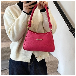 Detail of rose red shoulder bag with floral lace embossing and woven knot handle
