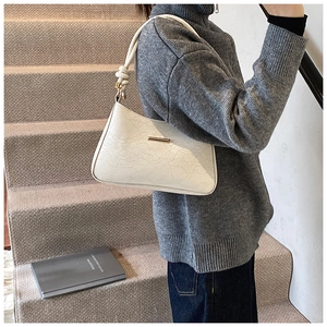 Detailed close-up of white lace texture and gold buckle on a stylish shoulder baguette bag