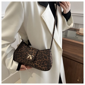 Close-up of leopard print shoulder bag featuring a golden metal bow buckle detail