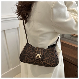 Chic leopard print crescent bag with golden bow clasp shown on a white wool coat