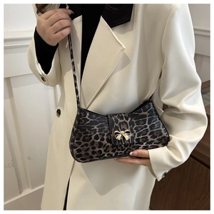 Nahaufnahme der Leoparden-Schultertasche mit goldener Schmetterlingsschnalle am Umschlag
