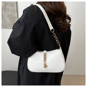 Detail van de minimalistische witte leren okseltas met gouden ketting en metalen gesp