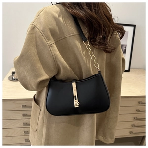Detail van klassieke zwarte lederen hobo-tas met gouden zuigersluiting en ketting