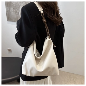 Detail of soft white tote bag featuring unique brown braided rope strap and metal eyelet