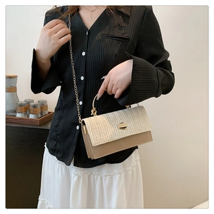Détail du sac à bandoulière en paille tissée avec poignée dorée et sangle chaîne