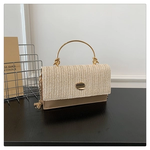 Close-up of woven straw and brown leather shoulder bag with golden round handle