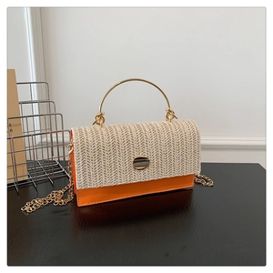 Detail of straw woven texture and orange leather trim on a chic summer crossbody bag