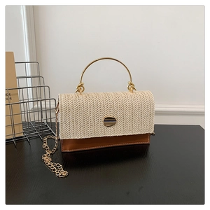 Detail of retro straw woven and brown leather crossbody bag with round metal handle