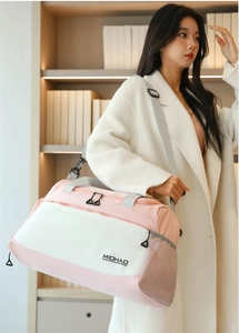 Detail of pink and white travel bag featuring adjustable shoulder strap and mesh pocket