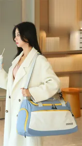 Blue and white large gym bag with yellow zippers shown on a model in a cozy interior
