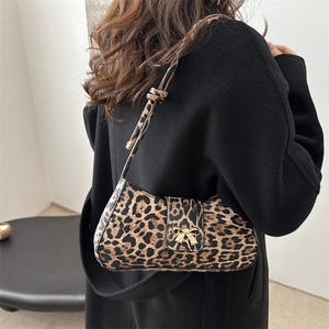 Schicke Baguette-Tasche mit Leopardenmuster und goldener Schleife zum schwarzen Mantel