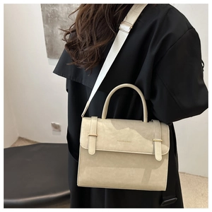 Sac bandoulière tendance blanc cassé avec bandoulière large sur manteau noir