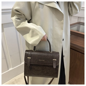 Détail du sac en similicuir marron foncé avec boucle dorée et lettrage FASHION & BAGS