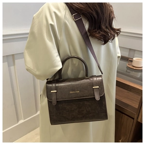 Brown leather crossbody bag with adjustable wide strap shown in a lifestyle setting