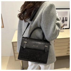 Vue détaillée du sac bandoulière en cuir noir mat avec lettrage doré et sangle réglable
