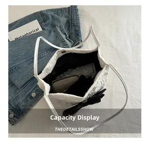 Détail d'un sac cabas blanc texturé avec nœud noir montrant une grande capacité interne