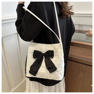 Détail du tissu texturé blanc et du grand nœud noir de ce sac seau élégant pour femmes