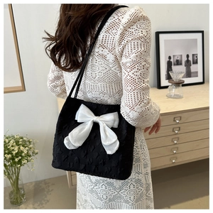 Détail de la texture 3D embossée et du grand nœud blanc sur le sac cabas noir