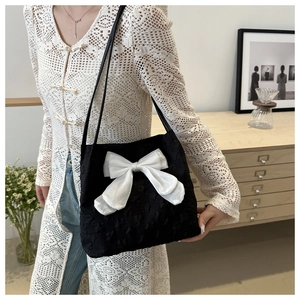 Détail du sac cabas noir avec nœud blanc et texture florale sur une tenue chic