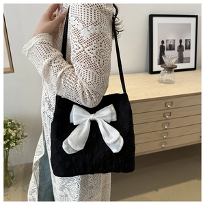 Vue latérale du sac porté épaule en jacquard noir avec un grand nœud en satin crème
