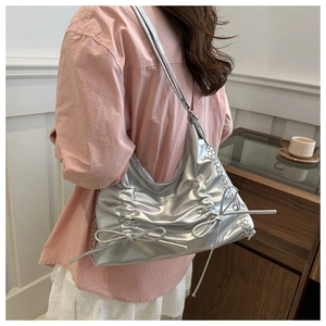 Detail of silver pleated shoulder bag with metallic finish and bow ornaments