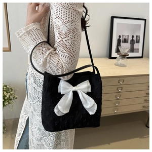 Détail du sac bandoulière noir élégant orné d'un grand nœud blanc en organza chic