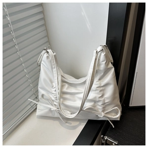 Detail of white tote bag featuring side pleats and delicate ribbon bow accents