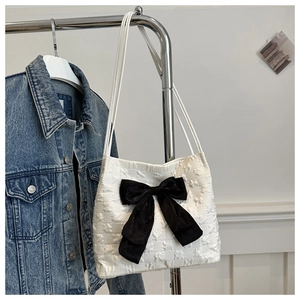 Détail du sac cabas blanc à texture étoilée avec un grand nœud en velours noir suspendu