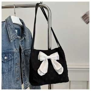 Détail du sac cabas noir avec un grand nœud en organza blanc sur tissu texturé