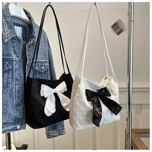 Détail du tissu jacquard à étoiles avec nœud contrasté sur deux sacs à bandoulière
