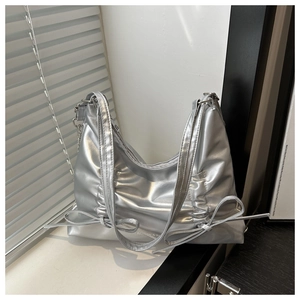 Silver metallic hobo bag with pleated details and bow accents in a minimalist setting