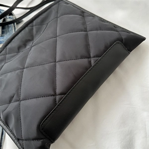 Gros plan sur le sac fourre-tout en nylon noir matelassé avec surpiqûres en losanges