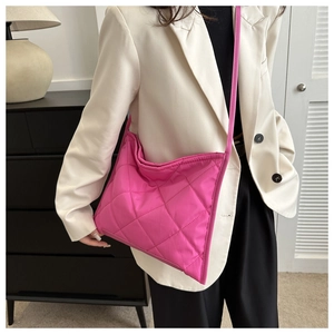 Detail of hot pink quilted shoulder bag with large diamond stitching and a slim strap