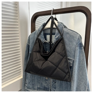 Sac bandoulière matelassé noir avec une veste en jean sur un cintre de mode