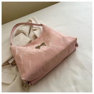 Detailed close-up of pink patent leather shoulder bag with silver metallic bow accent