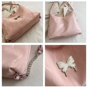 Detail of pink hobo bag with metallic butterfly ornament and silver chain strap